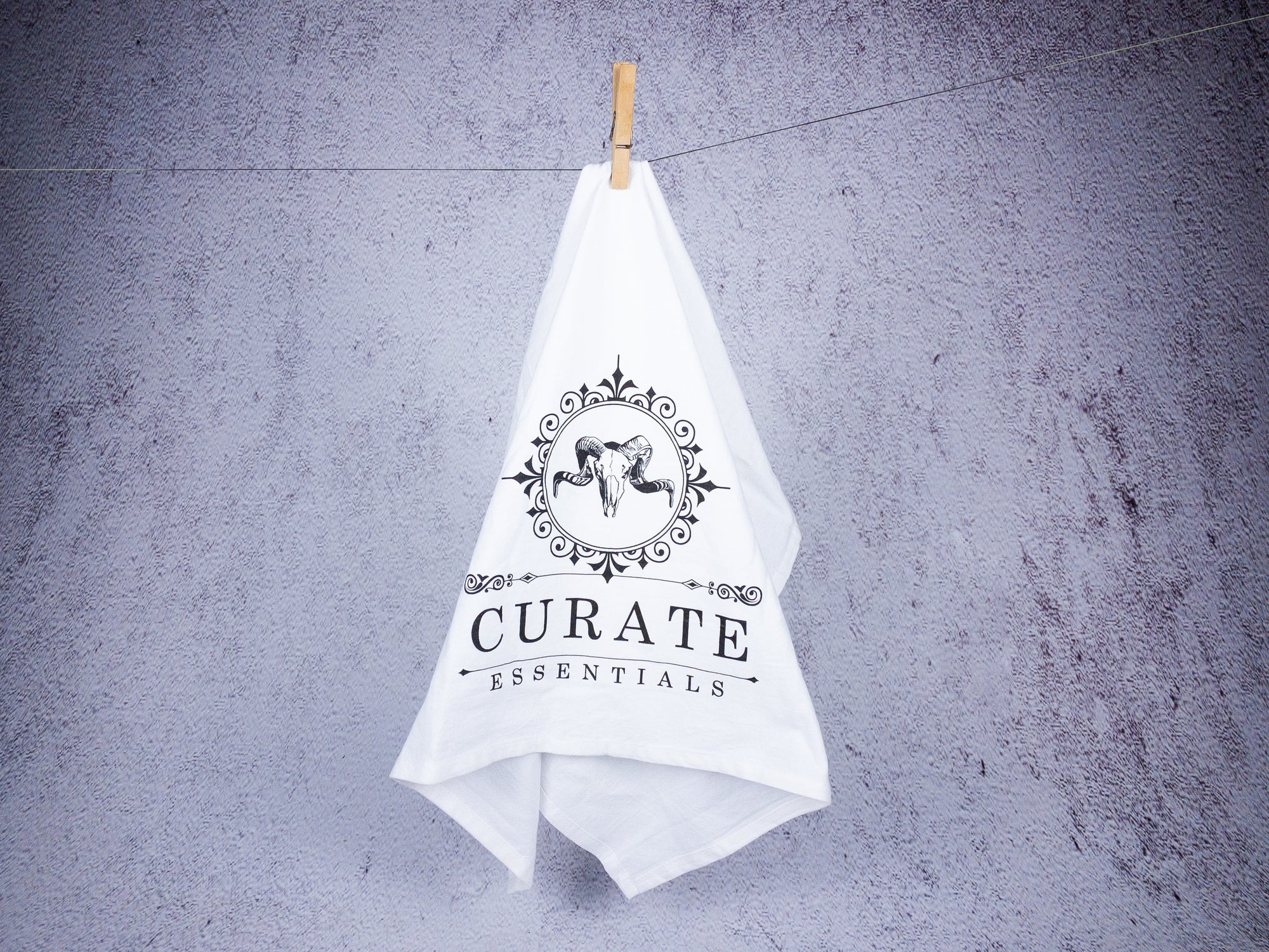 white tea towel with curate essentials logo